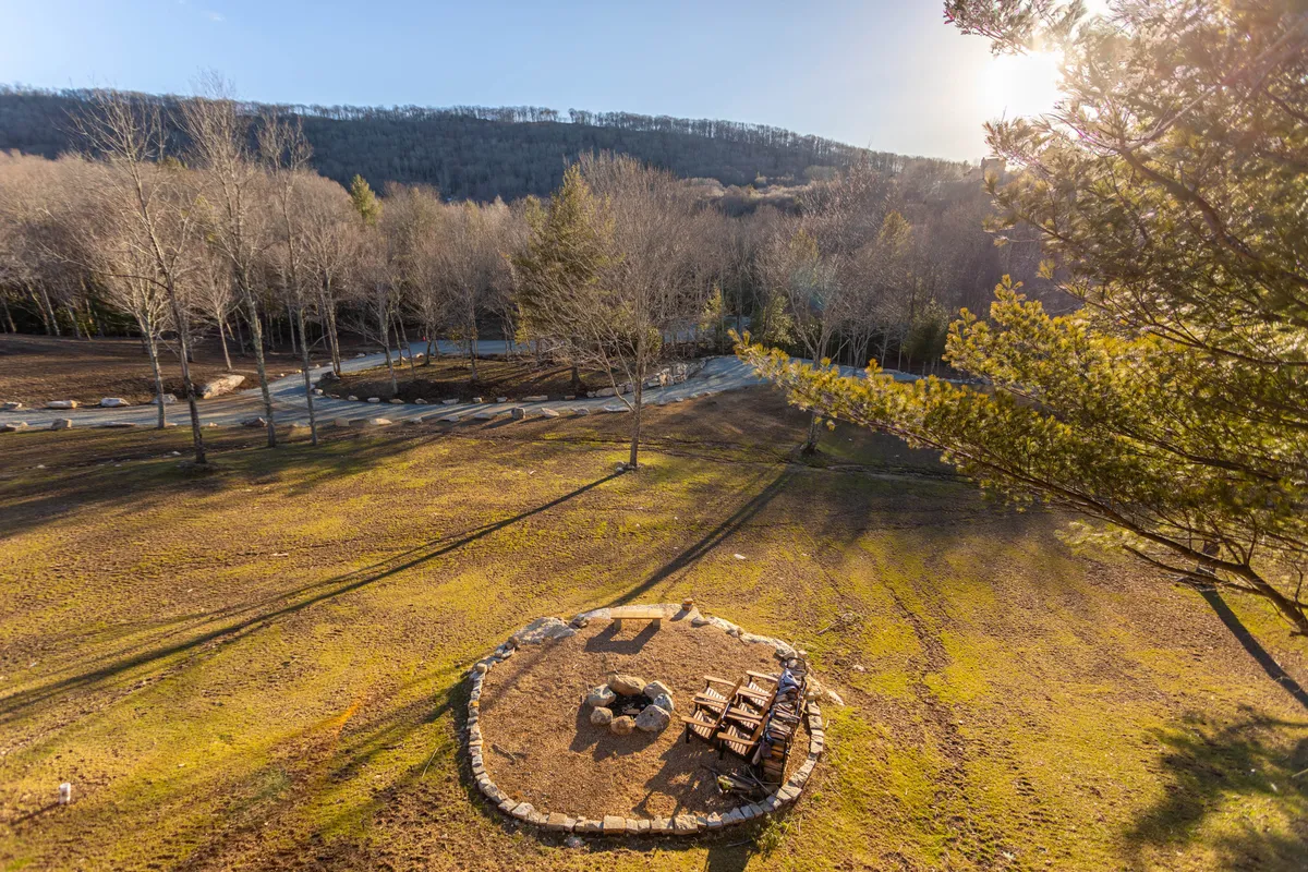 An outdoor area featuring a fire pit and picnic table nestled among tall trees, creating an inviting space for families and friends to gather, share meals, and enjoy evenings under the stars.