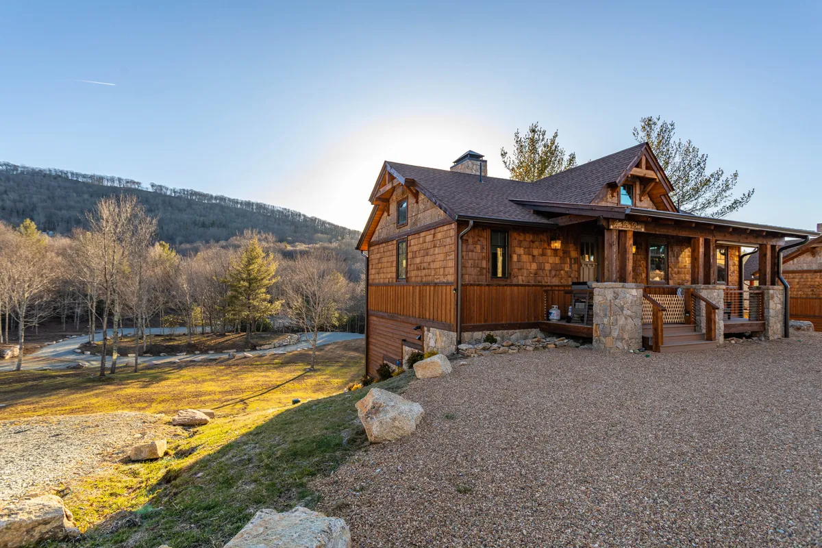 A serene exterior view of the home framed by surrounding trees and mountains, with a stone pathway leading up to the entrance. This natural setting hints at the proximity to trails and the abundance of outdoor activities, making it a perfect backdrop for gatherings or quiet reflection after active days.