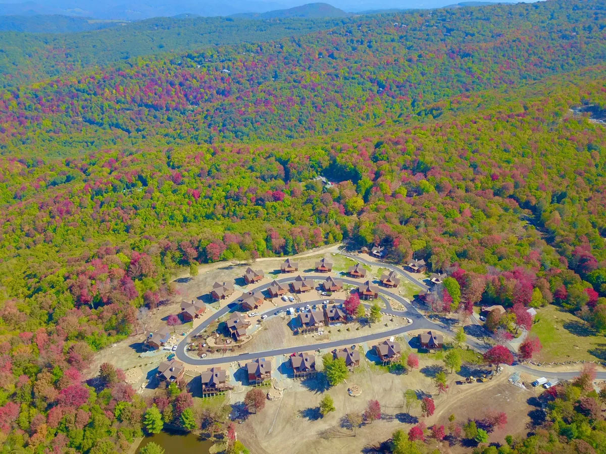 A wider shot capturing residential buildings nestled within a lush forest, with a winding road and a pond in view. The peaceful, communal landscape suggests opportunities for hiking, community gatherings, and seasonal events—highlighting the social and exploratory atmosphere of Eagles Nest.